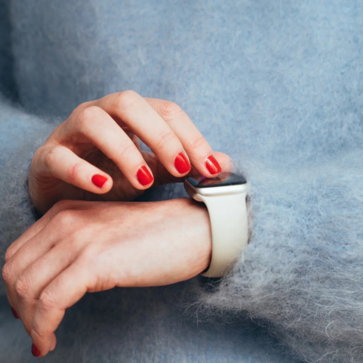 Close-up of female hand adjusting smartwatch on wrist. Concept of wearable technology, fitness tracking and modern lifestyle
